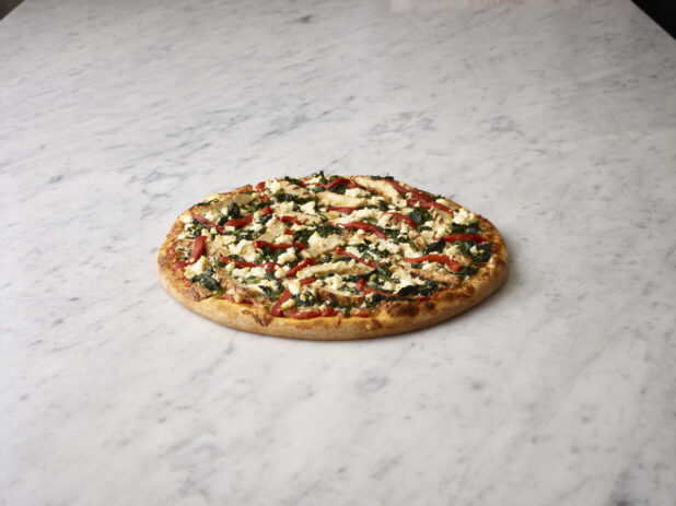Whole 4 topping pizza with chicken, spinach, roasted red peppers and feta cheese on a white marble background