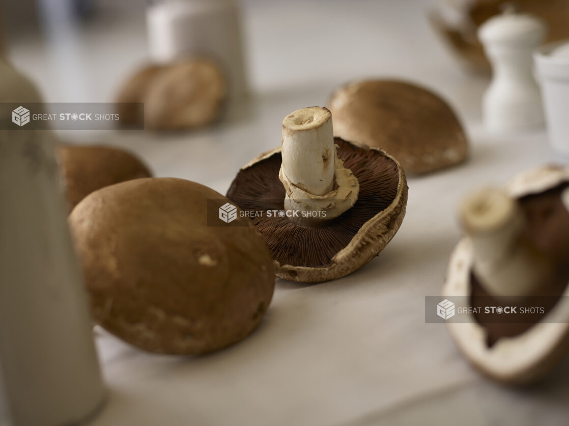 Whole portobello mushrooms in the foreground and background on a white linen background