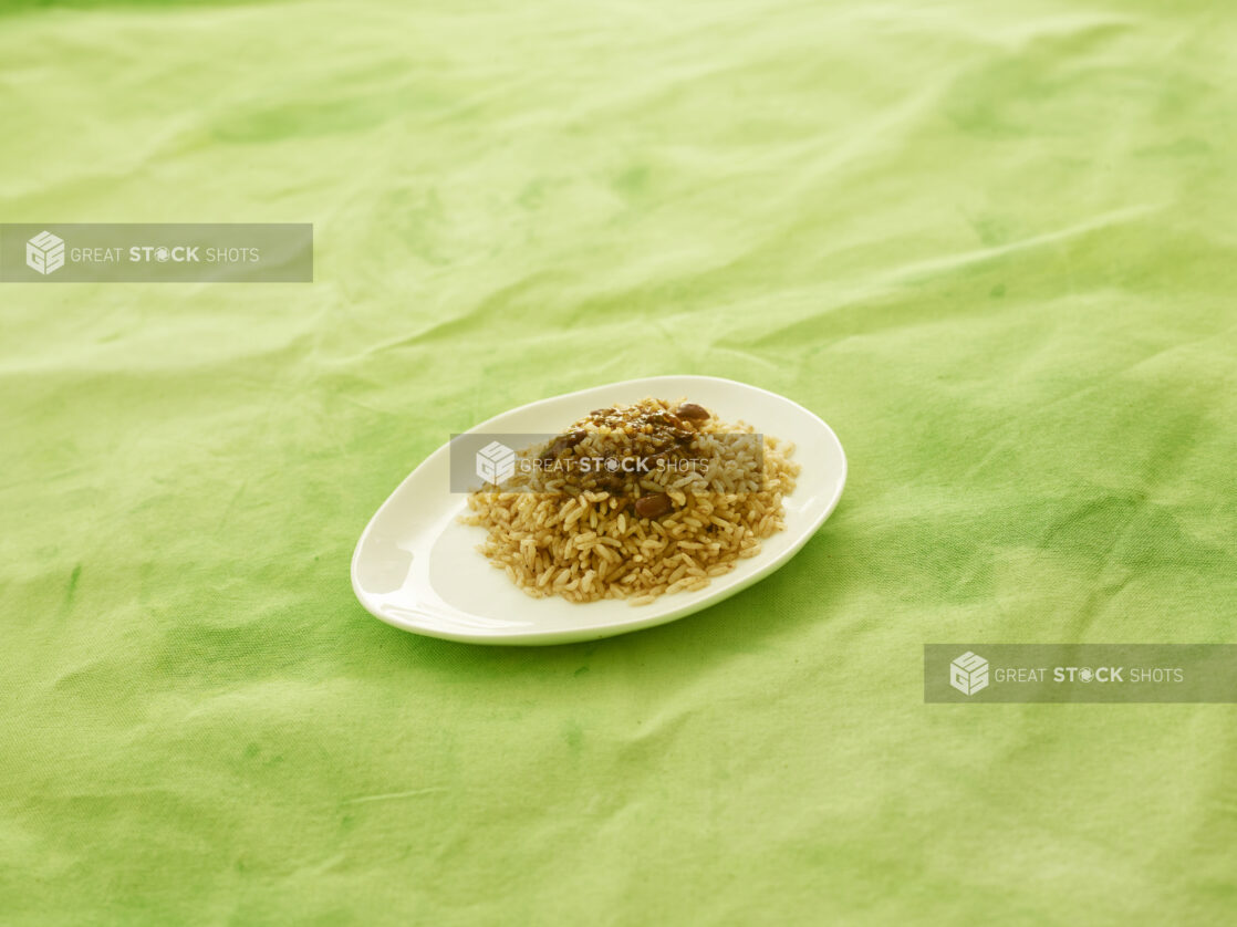 Caribbean rice and peas on white plate with lemon/lime green tablecloth