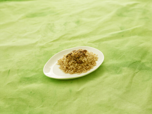Caribbean rice and peas on white plate with lemon/lime green tablecloth