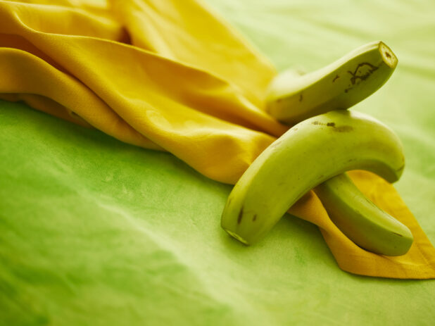 Green banana on orange cloth napkin on lemon/lime green tablecloth