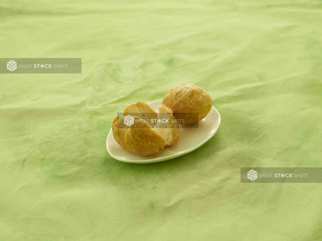 2 Caribbean fried dumplings on a white side plate on a lemon/lime green background