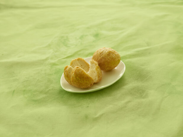 2 Caribbean fried dumplings on a white side plate on a lemon/lime green background