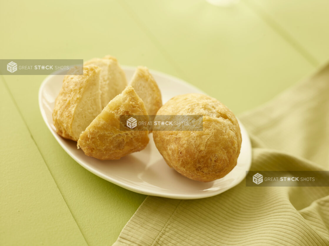 2 Caribbean fried dumplings, on a white side plate on a pale green table