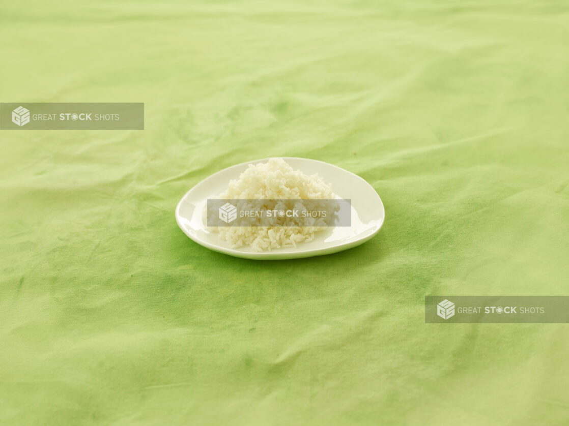 Side dish of white rice on white side plate on a lemon/lime green tablecloth