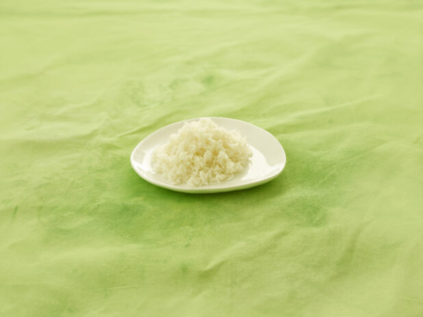 Side dish of white rice on white side plate on a lemon/lime green tablecloth