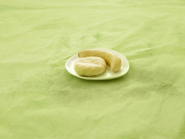 Caribbean boiled dumpling and boiled banana on a white side plate on a lemon/lime green tablecloth