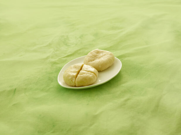 2 Caribbean boiled dumplings on a white side plate on a lemon/lime green tablecloth