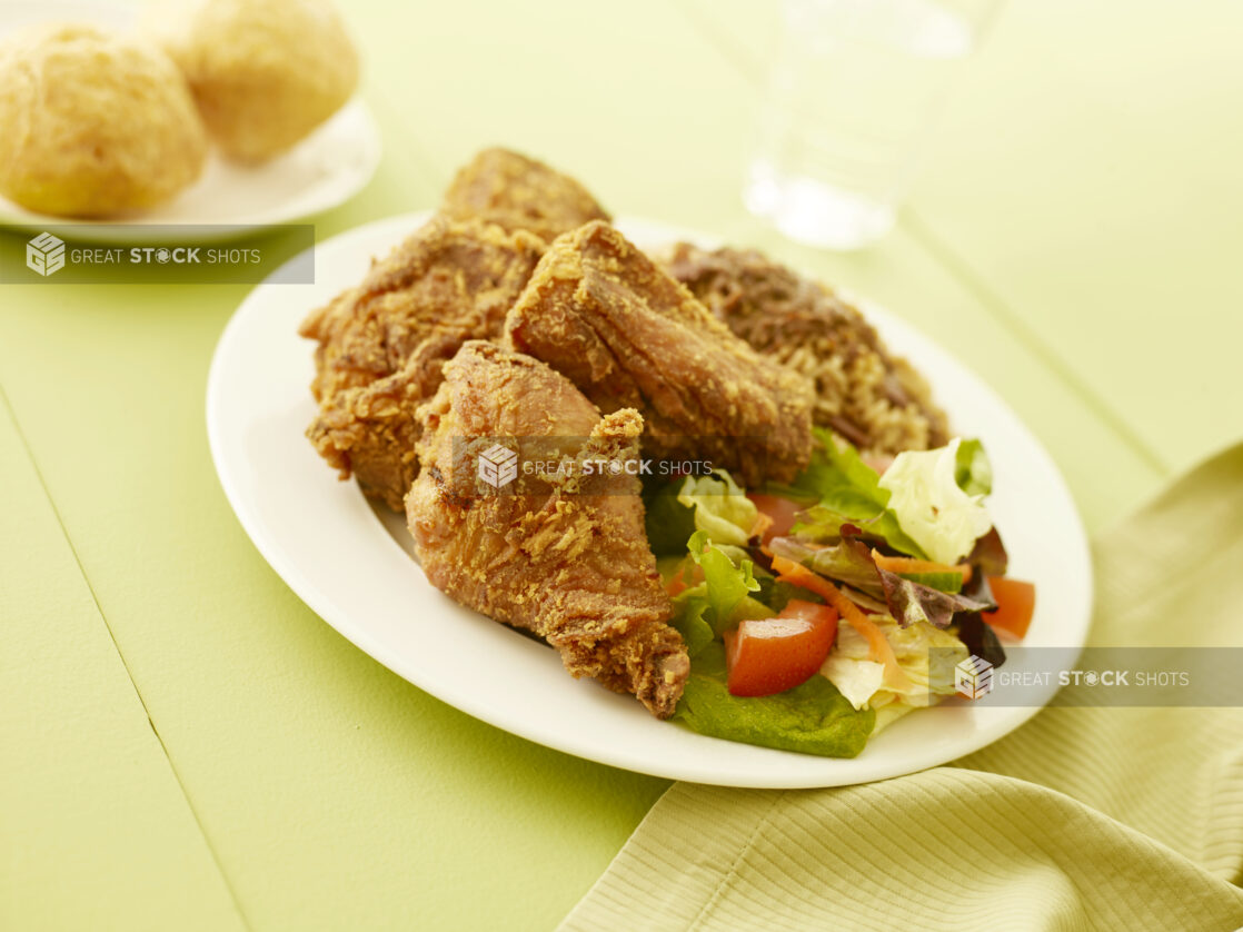 Fried chicken with salad on oval white plate on a pale green table