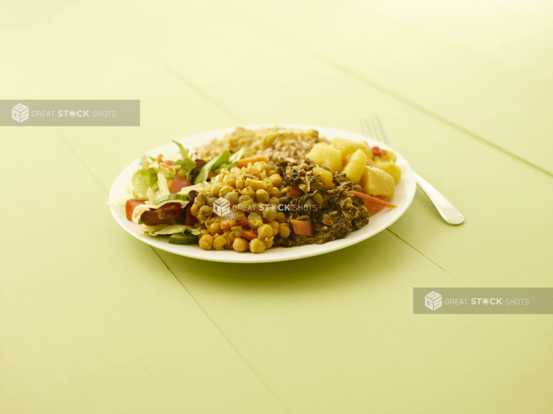 Caribbean vegetarian dinner on a round white plate on a light green table