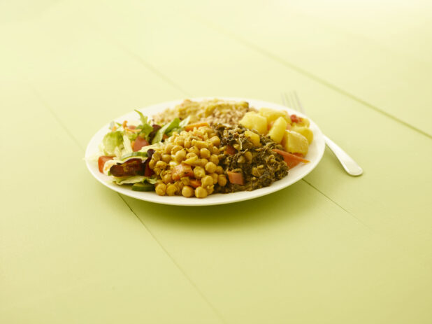 Caribbean vegetarian dinner on a round white plate on a light green table