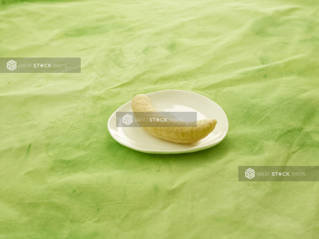 Boiled plantain on a white side plate on a lemon/lime green tablecloth