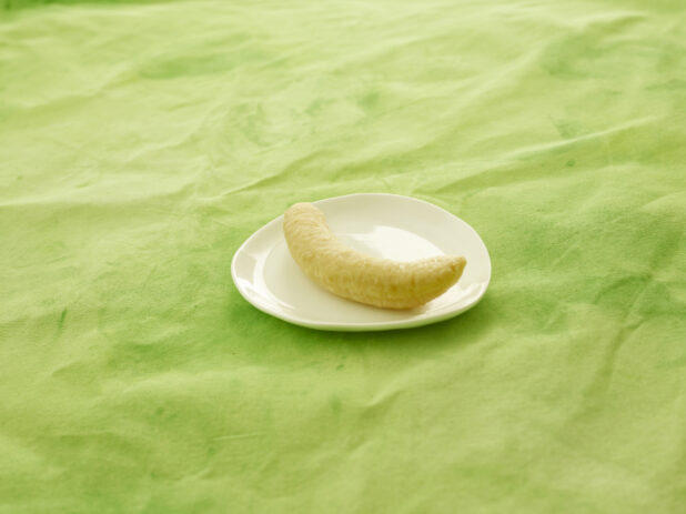 Boiled plantain on a white side plate on a lemon/lime green tablecloth