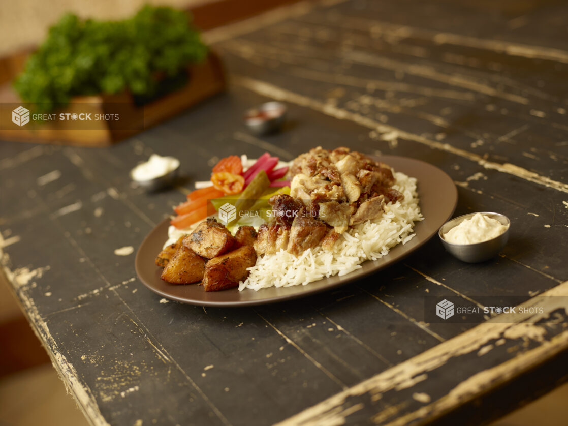 Chicken shawarma dinner with rice, potatoes and salad with a box of parsley in the background