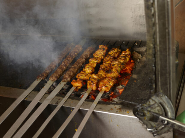 BBQ'd Beef kafta and chicken on metal skewers on an indoor BBQ