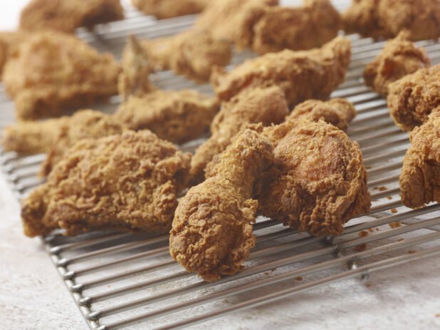 Close up view of fried chicken on a baking rack on a white background