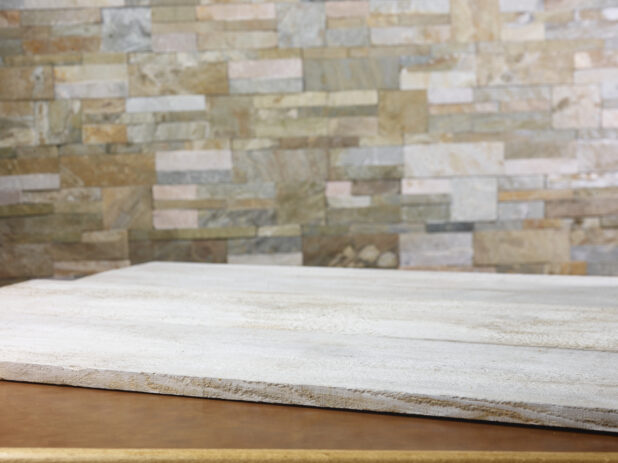 Rustic white wooden planks on a table with a limestone wall in the background