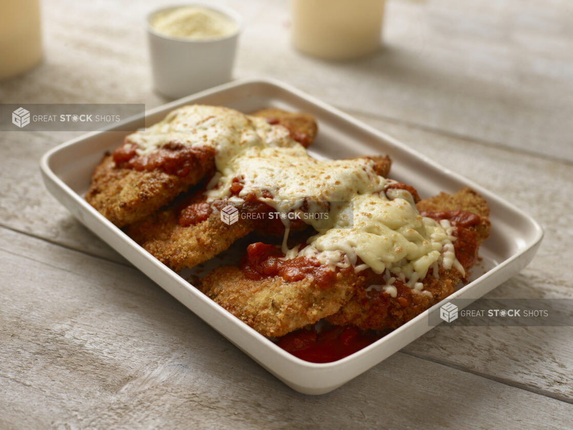 Chicken parmesan in a white platter on a wooden table