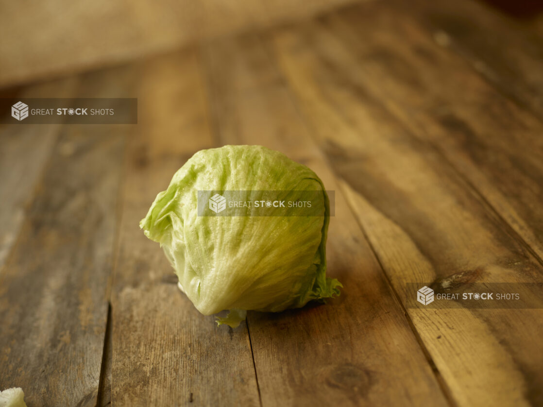 whole head of iceberg lettuce centered on an aged wooden table,