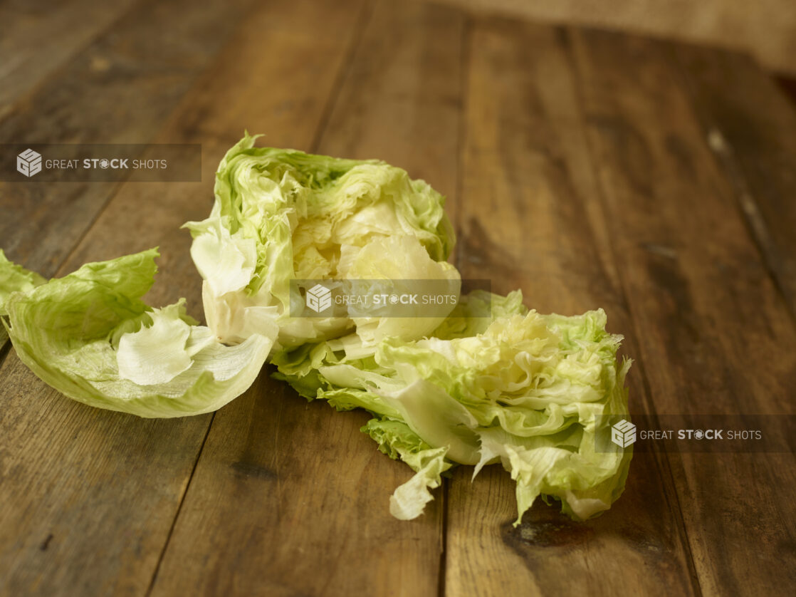 Fresh iceberg lettuce torn open on a rustic wooden table, straight on view