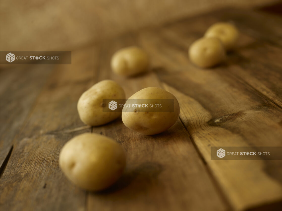 Whole uncooked potatoes on a rustic wooden table shot on a 45 degree angle