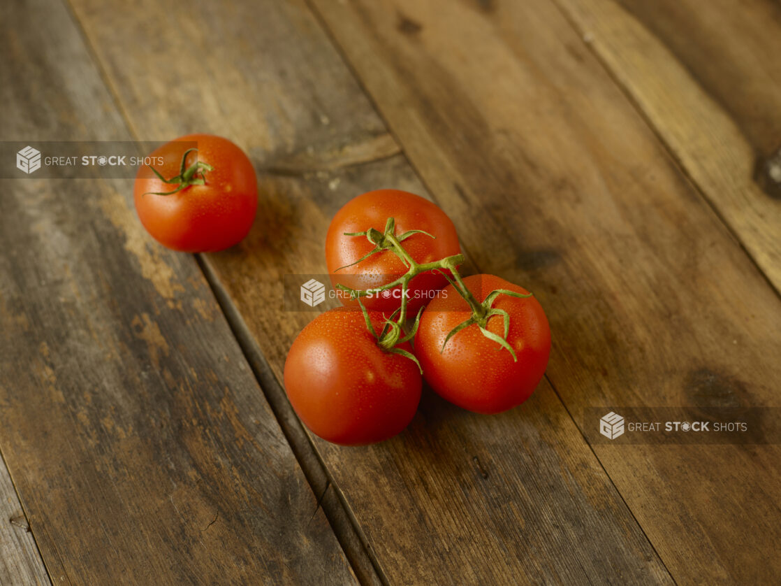 Whole tomatoes on the vine on a rustic wooden table on a 45 degree angle