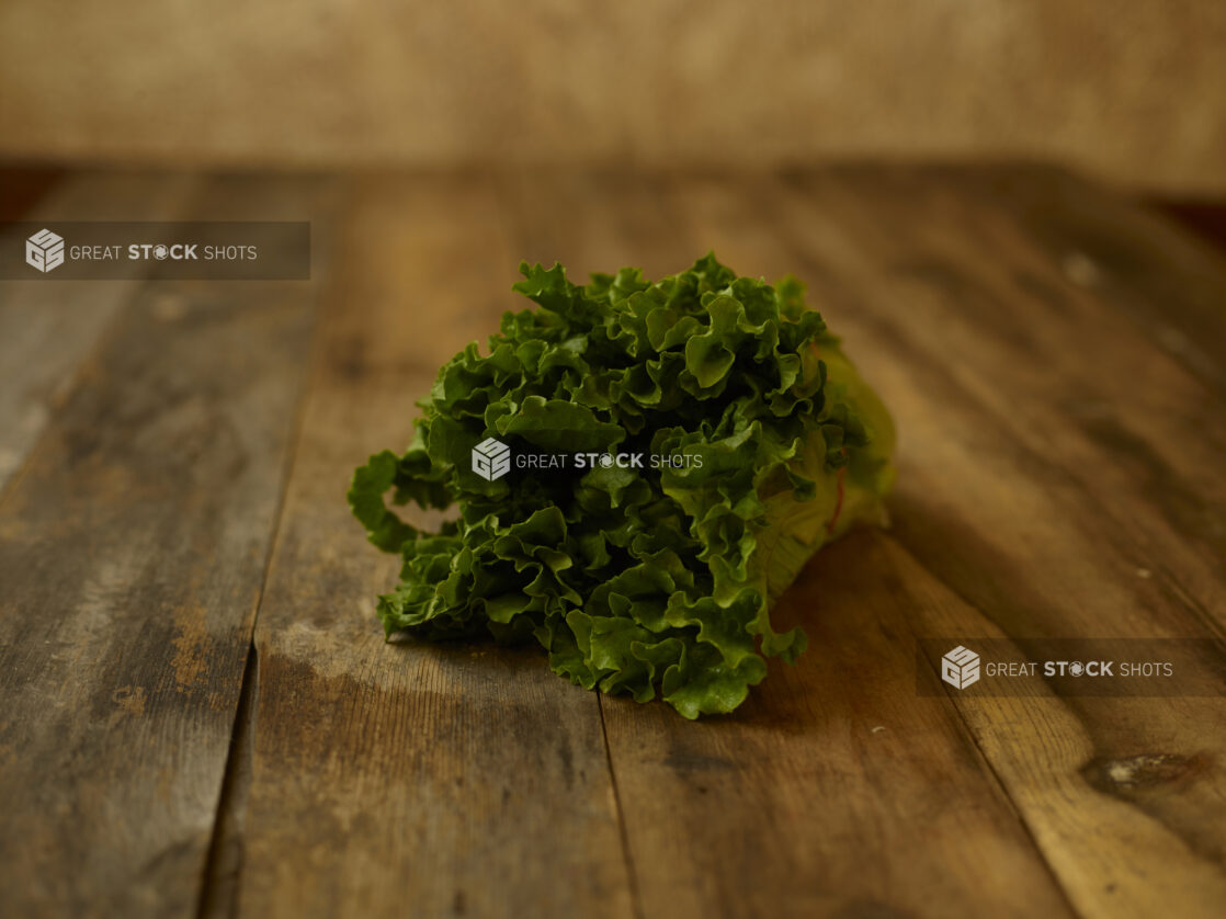 Whole head of leaf lettuce on a aged wooden table