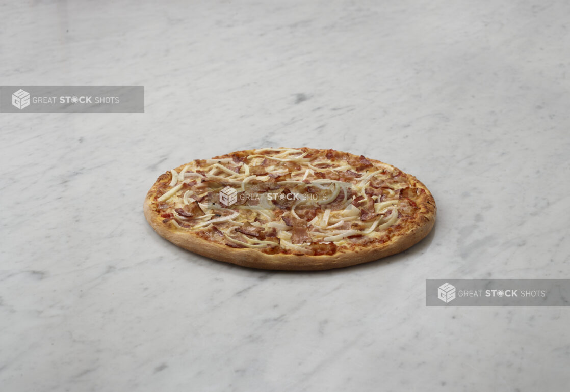 2 topping onion and bacon pizza on a white marble table, straight on view