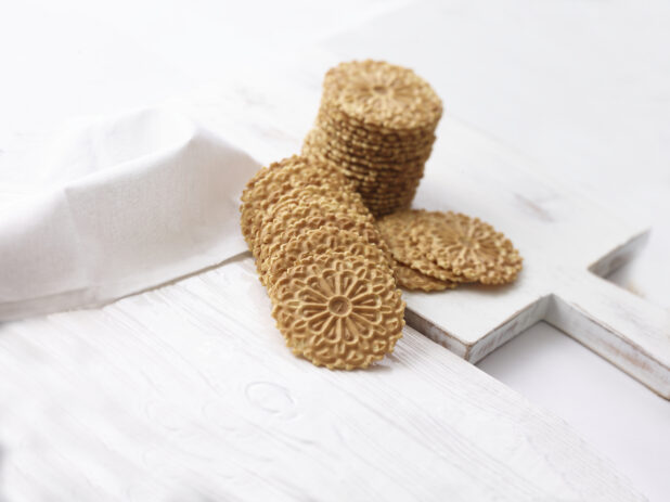 Pizzelle, Italian waffle cookies, on white wooden background, shot on an angle