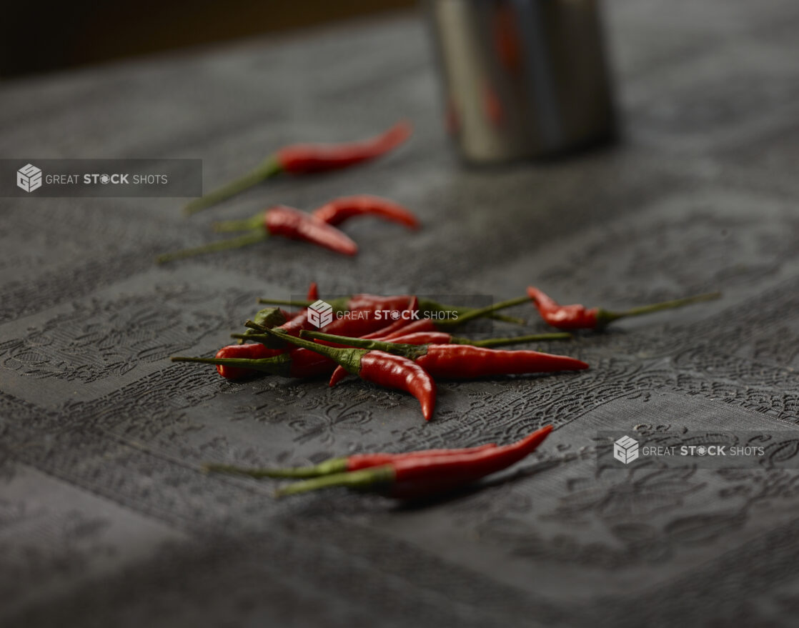 Small whole red chilli peppers on a black lace tablecloth, close-up, select focus