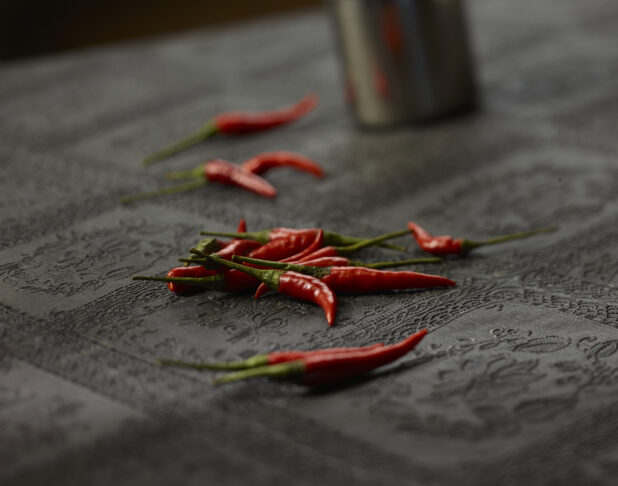 Small whole red chilli peppers on a black lace tablecloth, close-up, select focus