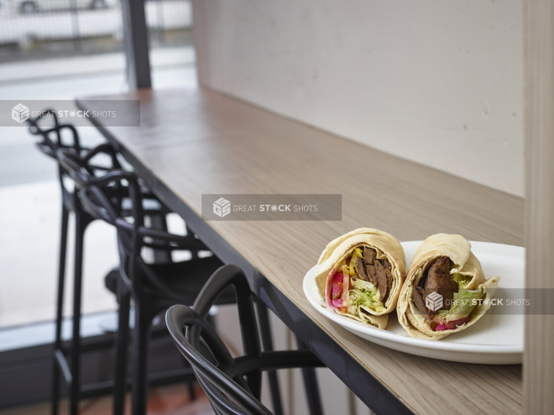 Middle eastern gyro pita on a plate sitting on top of a wooden table in a restaurant