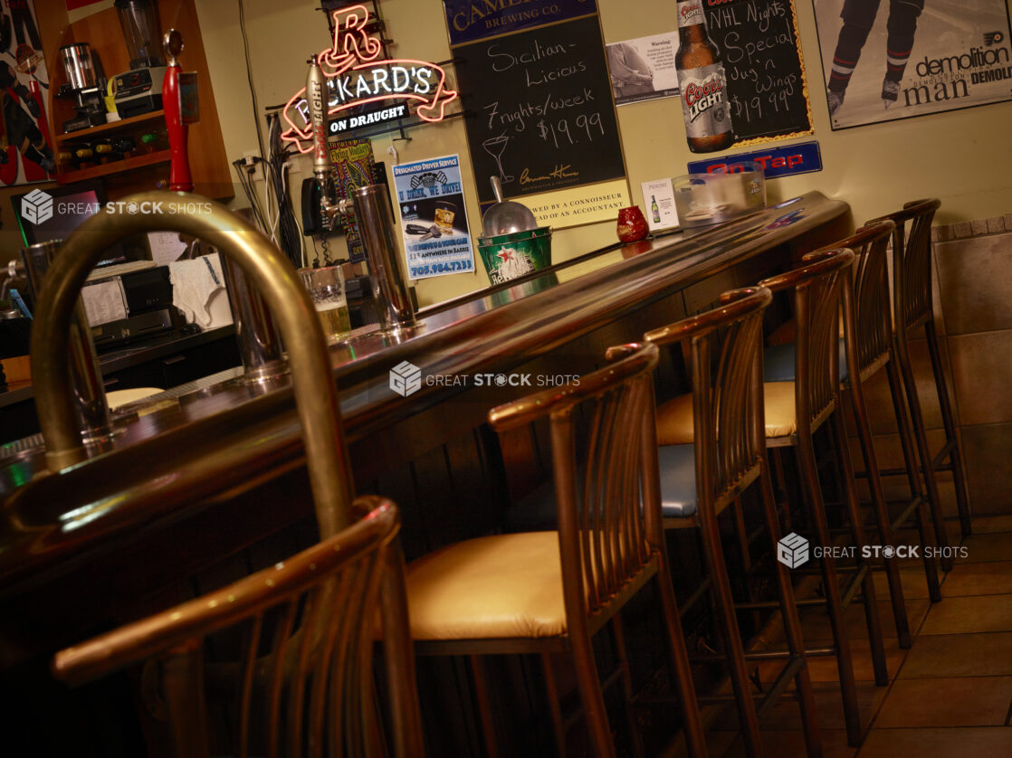 Bar with stools inside of a dimly lit restaurant