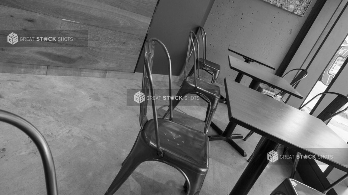 Black and white shot of empty fast food restaurant tables and chairs, tilted angle