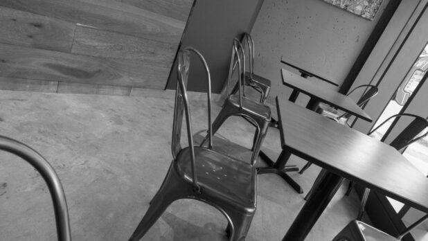 Black and white shot of empty fast food restaurant tables and chairs, tilted angle