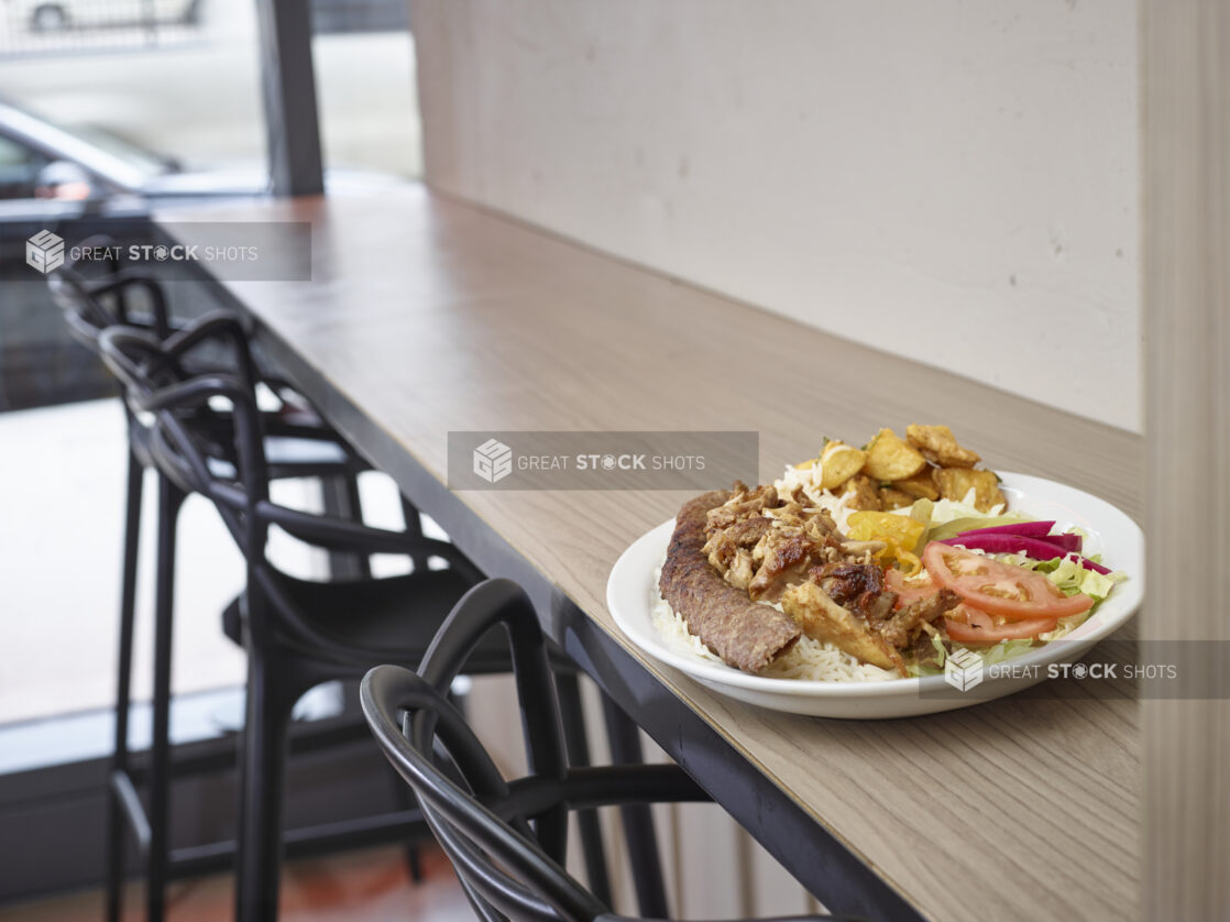 Middle eastern plate of mixed meats, rice, salad and potatoes on a plate in a restaurant