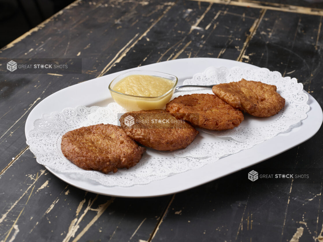 A Platter of Potato Latkes - Potato Pancakes - with a Side of Apple Sauce on a Dark Wooden Table