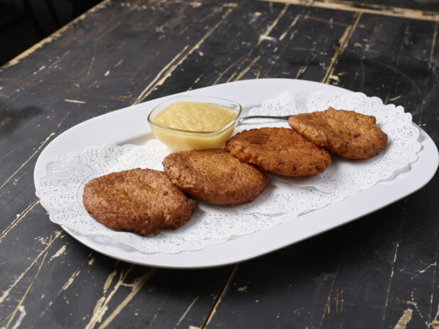 A Platter of Potato Latkes - Potato Pancakes - with a Side of Apple Sauce on a Dark Wooden Table