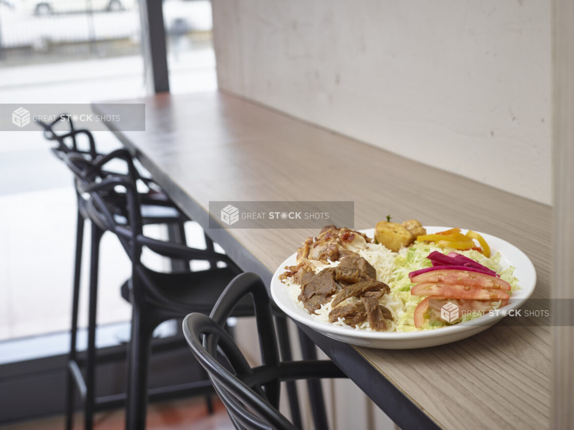 Middle eastern plate of mixed meats, rice, salad and potatoes on a plate in a restaurant