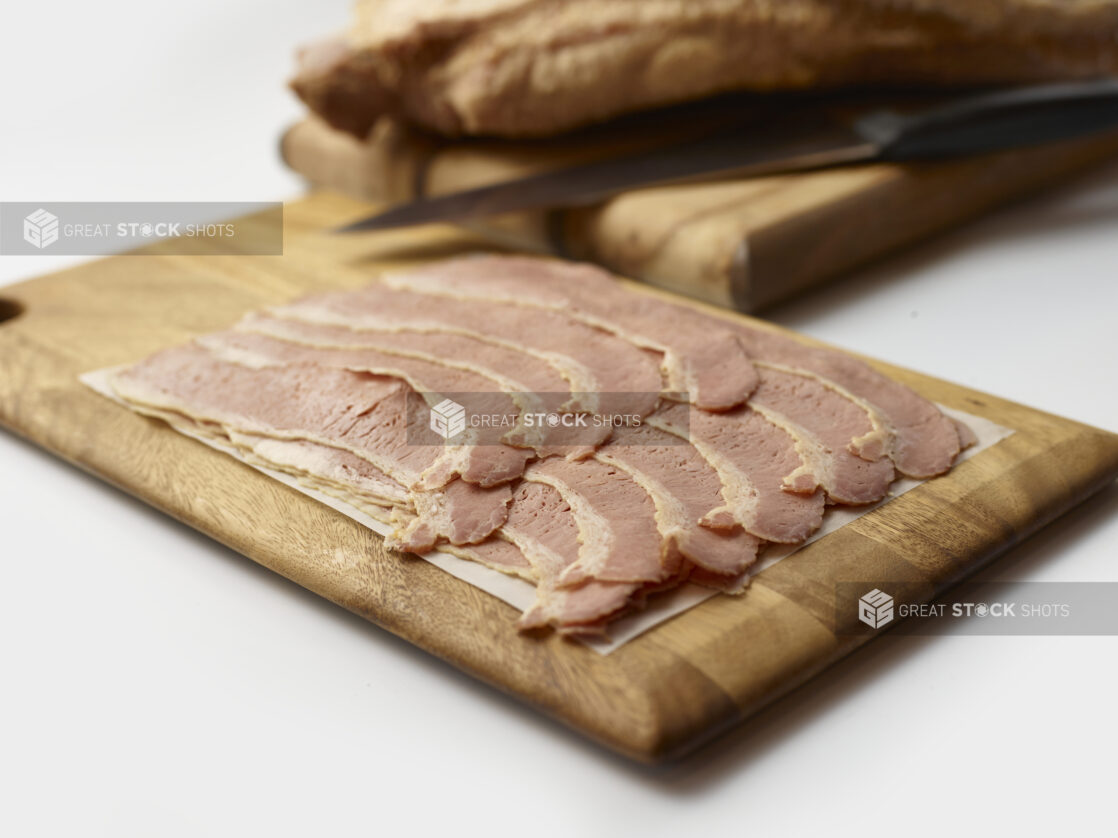 Thin slices of corned beef arranged on a wood board, background objects, white background