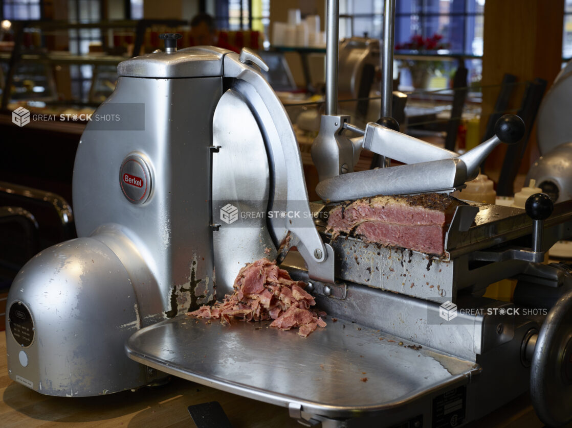 Corned beef being sliced in a commercial meat slicer