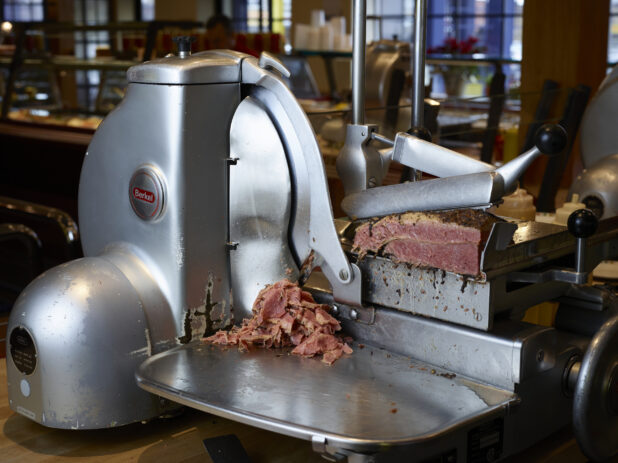 Corned beef being sliced in a commercial meat slicer