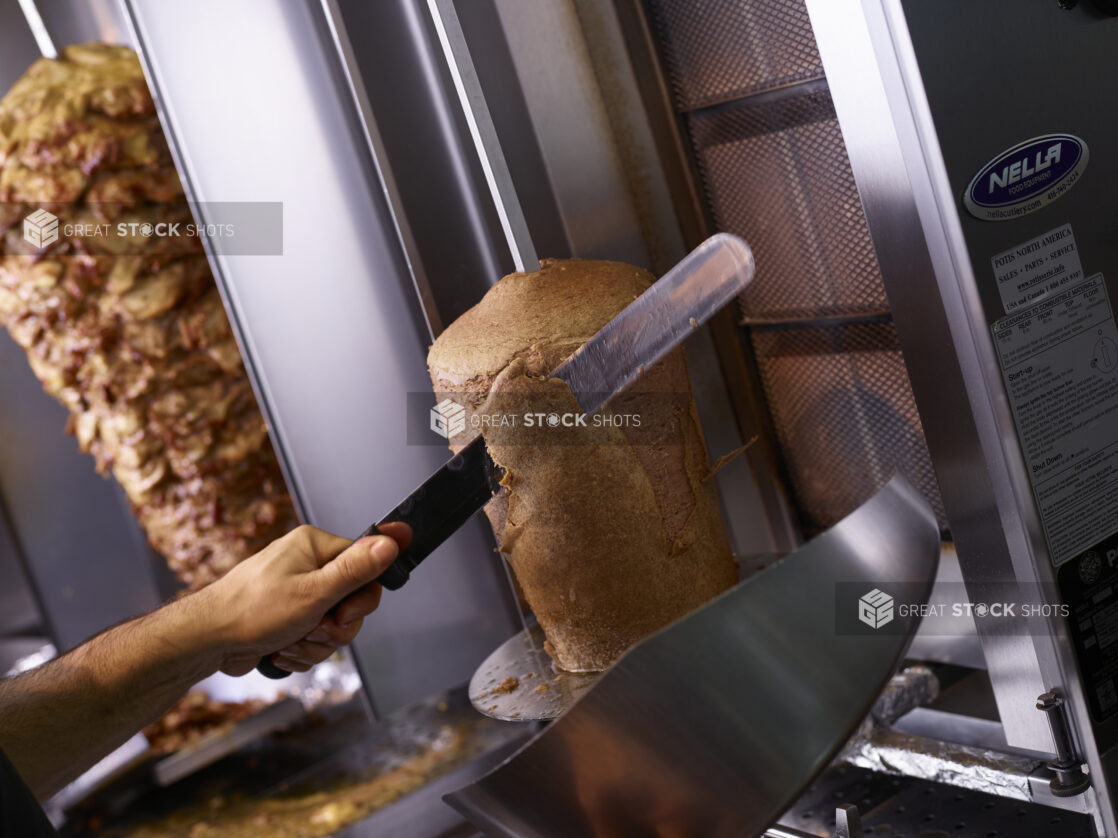 Man carves meat off of a spit in a middle eastern restaurant