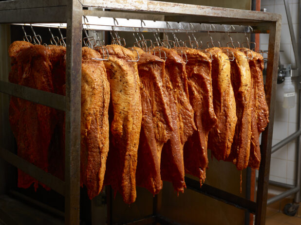 Smoked Pastrami Meat on Hooks in a Smokehouse of a Commercial Kitchen Setting