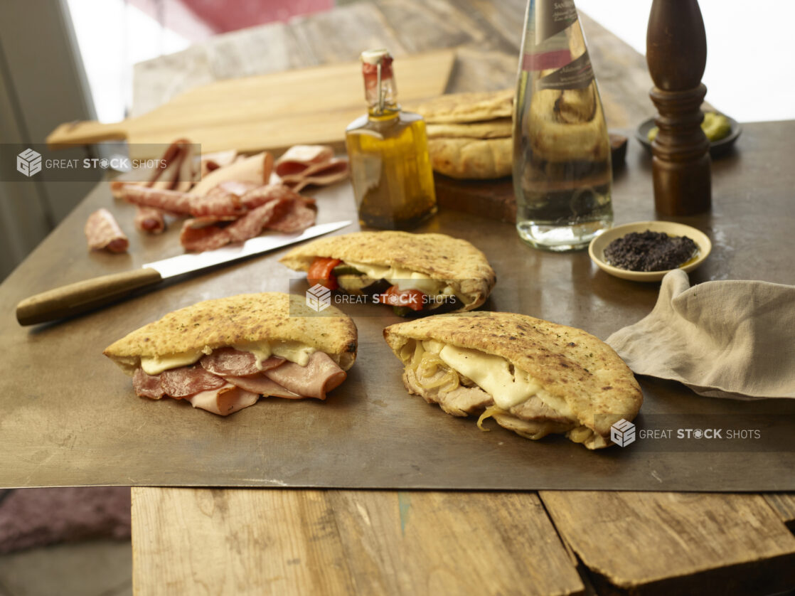 Assortment of stuffed pitas with melted cheese and ingredients in the background