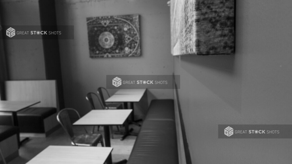 Black and white interior of an empty restaurant with seating and artwork on the wall