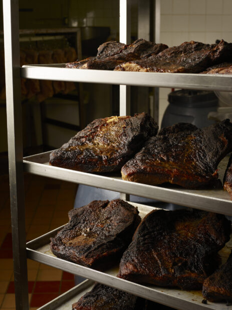 Trays of smoked beef brisket on a rack in a restaurant