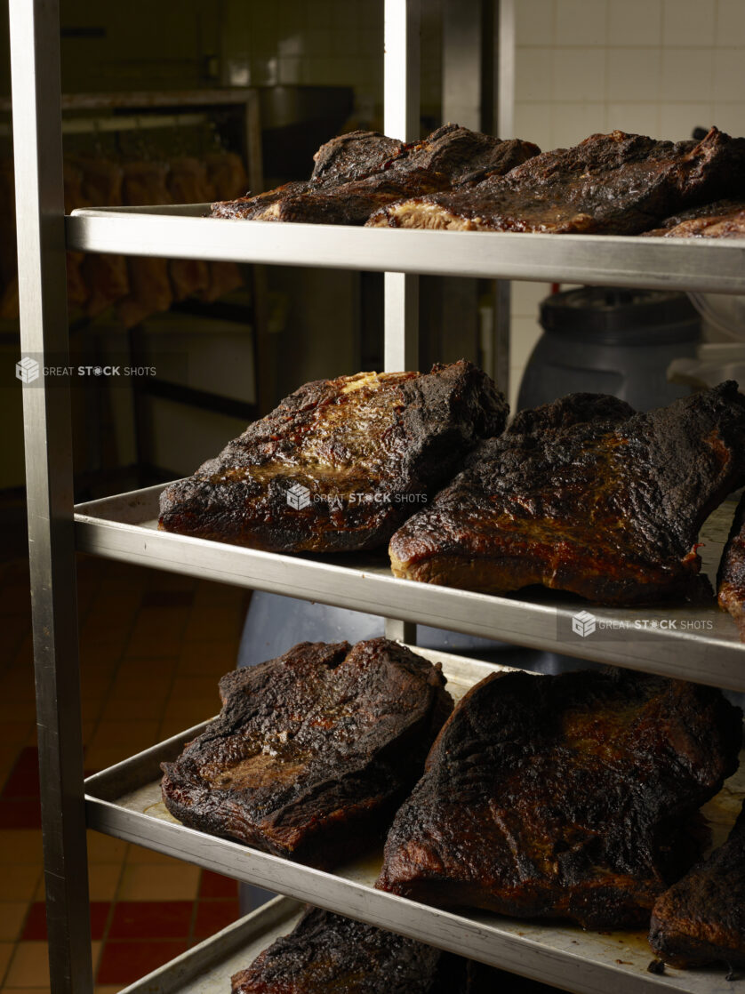 Trays of smoked beef brisket on a rack in a restaurant