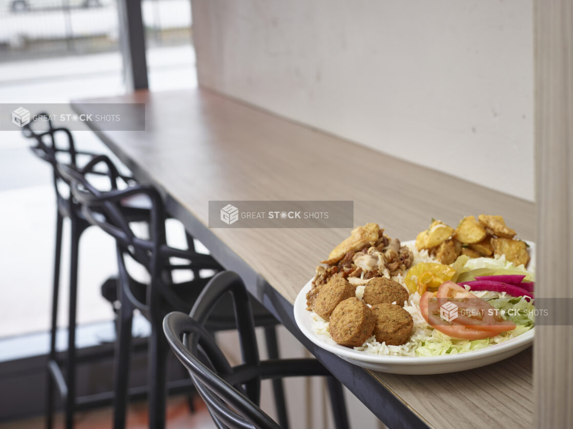 Middle eastern plate of falafel and shawarma, rice, salad and potatoes on a plate in a restaurant