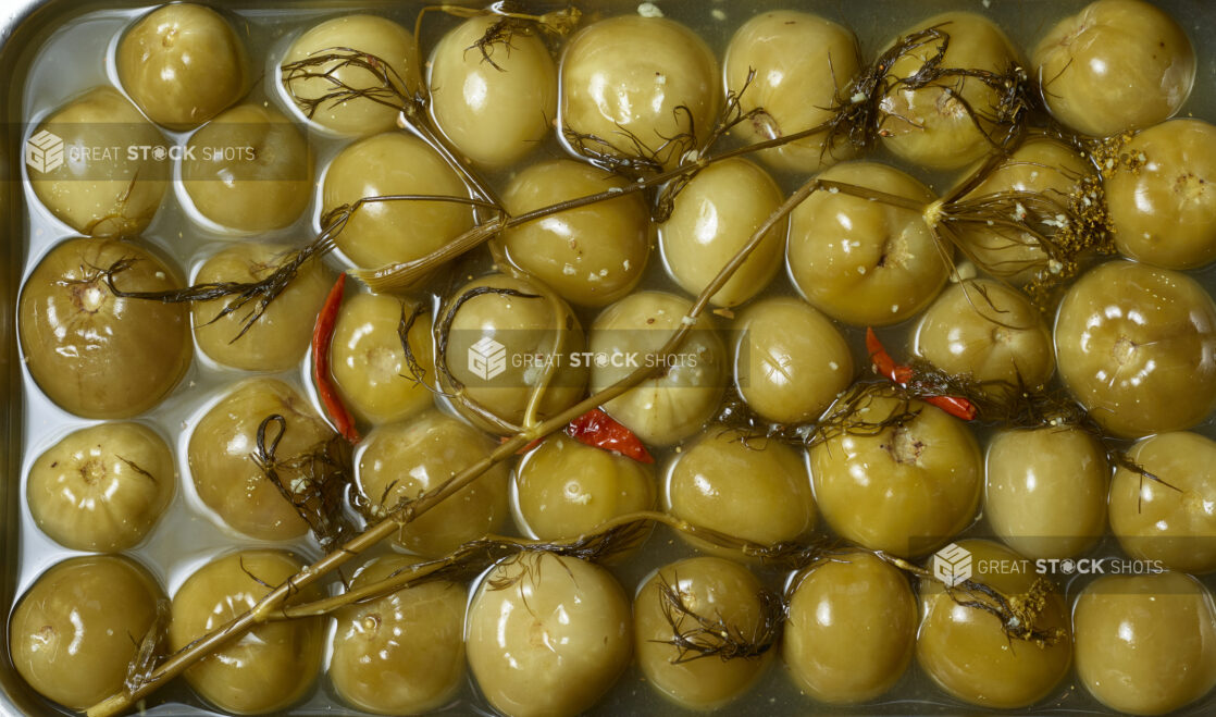 Whole sour green plums in brine, overhead